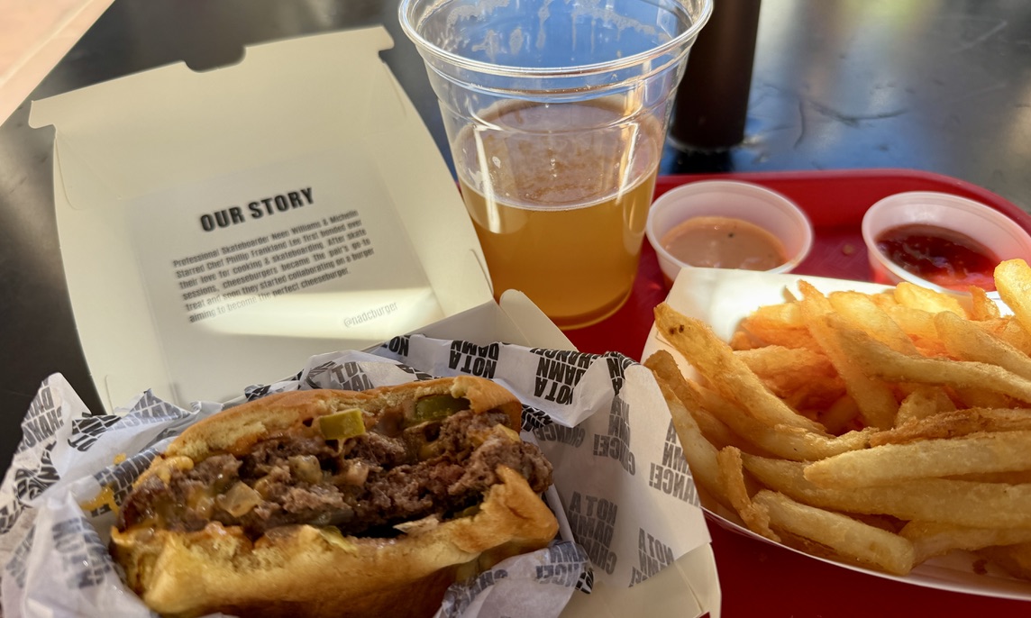 A cheeseburger, crinkle-cut fries and a beer on a red tray