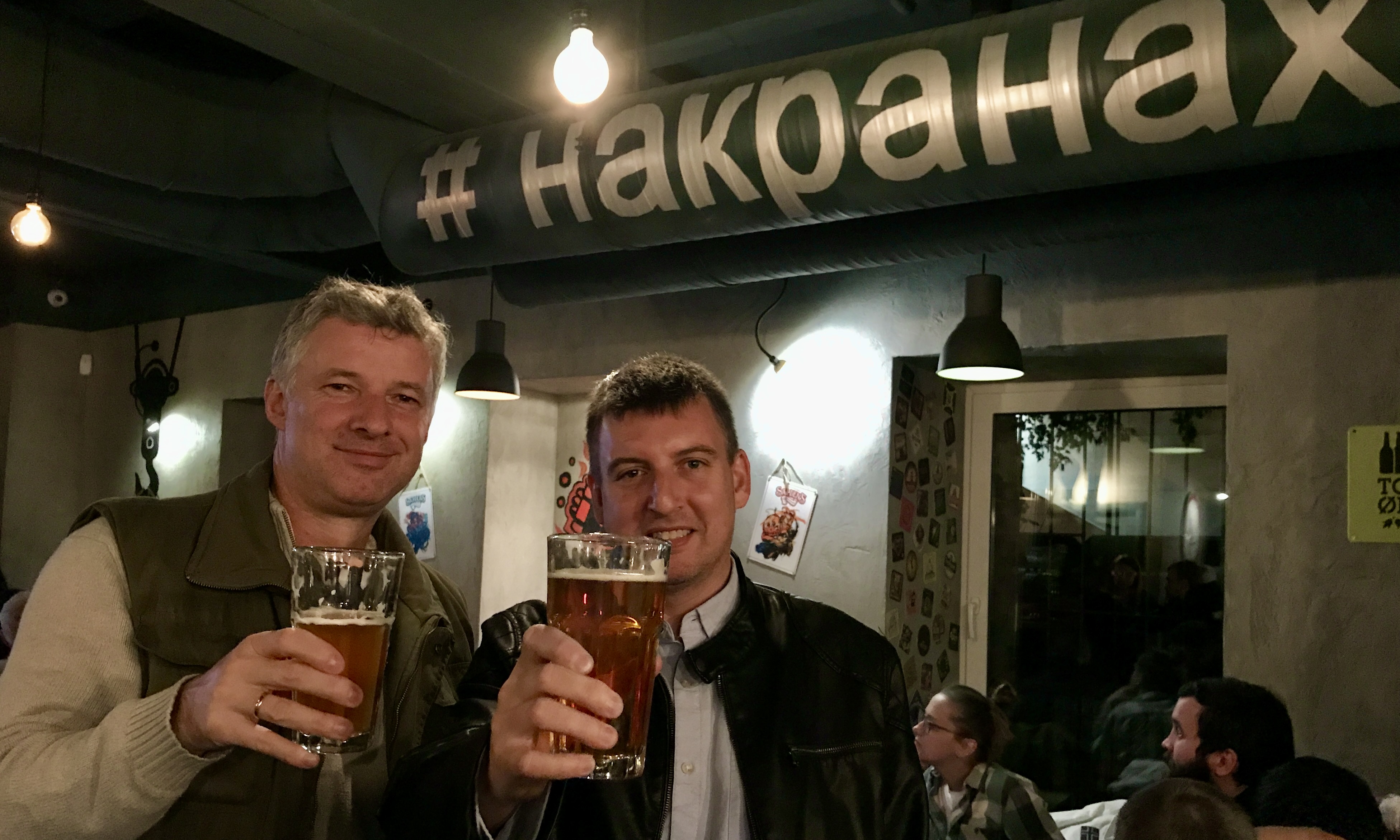 Raising two pints together in a Moscow beer bar