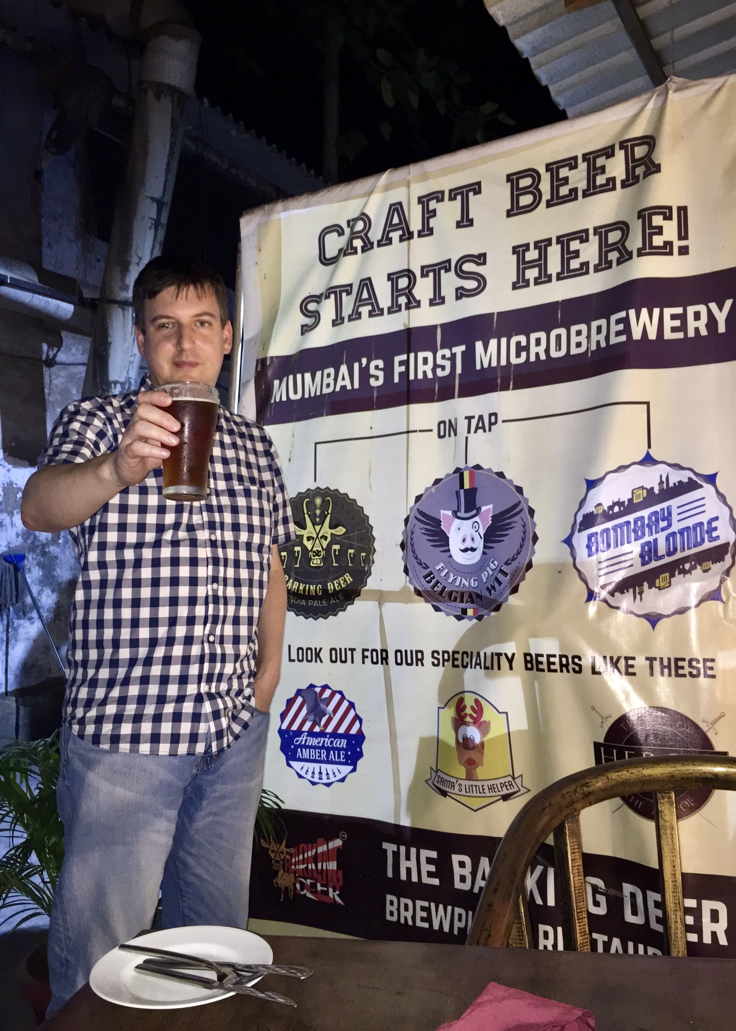 Rob with a pint at The Barking Deer in Mumbai, beside a craft beer sign